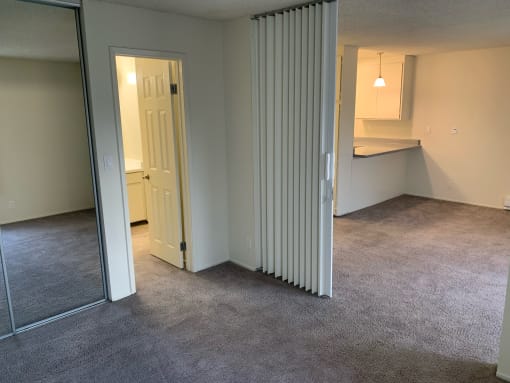 an empty living room with a door to a kitchen