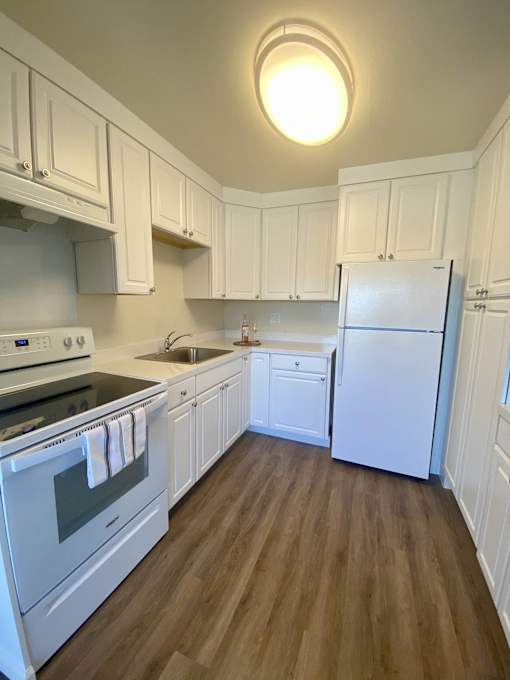 a kitchen with white cabinets and a white stove and refrigerator