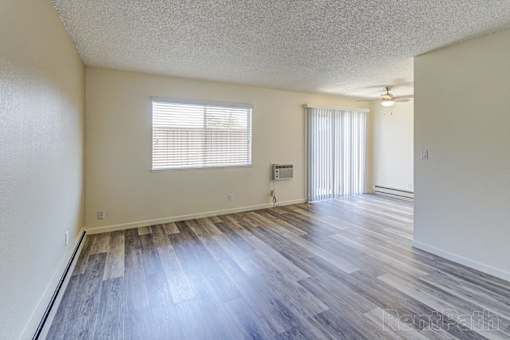 A room with wooden floors and a window with blinds.
