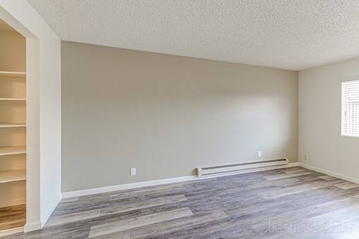 A room with a wooden floor and a window with blinds.