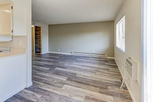 A room with wooden flooring and a window with blinds.