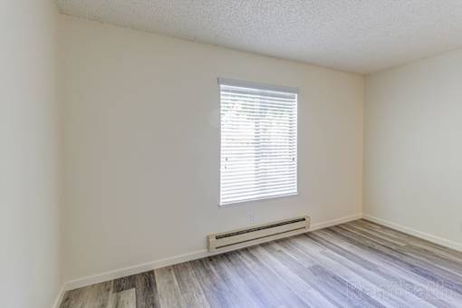 A room with a window and a radiator on the floor.