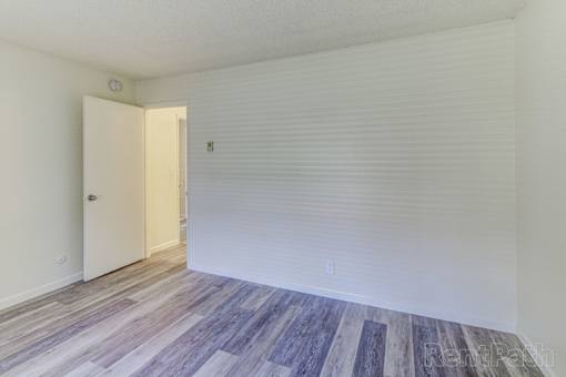 A room with a white door and a wooden floor.