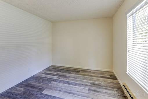 A room with a wooden floor and a window with blinds.