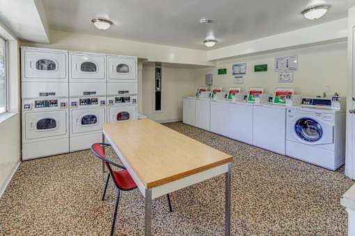 A laundry room with a table and chairs and washing machines.