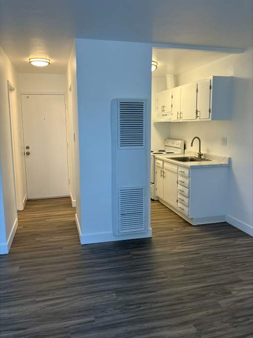 an empty kitchen with white cabinets and a white refrigerator