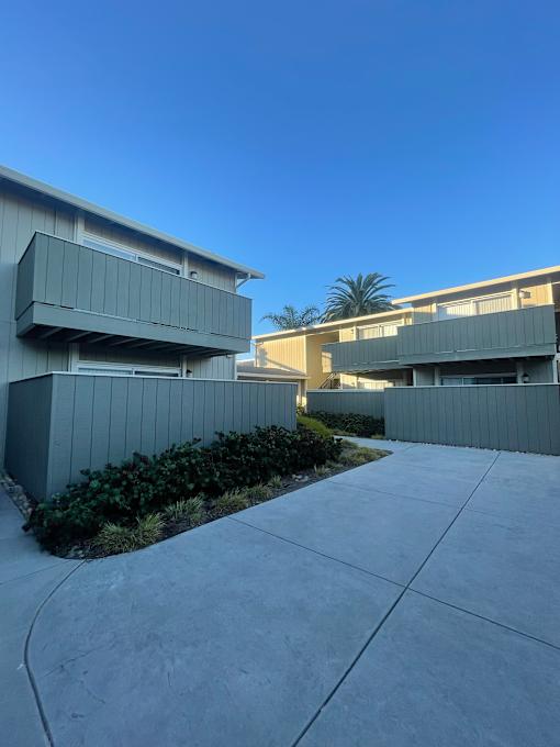 A modern building with a grey exterior and a clear blue sky in the background.