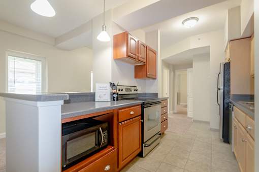 Kitchen area of an apartment fitted with stainless steel appliances, spacious cabinets, and tiled flooring at Park Lane Villa.