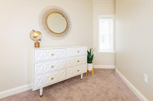 Bedroom area of an apartment, fitted with a dresser and carpet flooring.