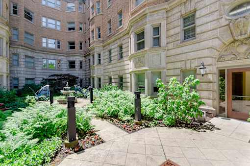 Courtyard area at Park Lane Villa apartments fitted with tiled walkway, greenery, and water fountain.