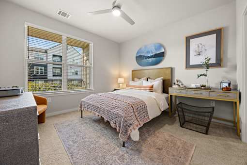 A bedroom with a bed, desk, chair, and window.