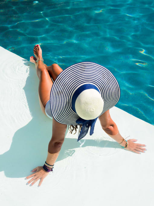a woman laying in the water wearing a floppy hat