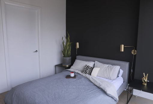 a bedroom with a bed and a black wall