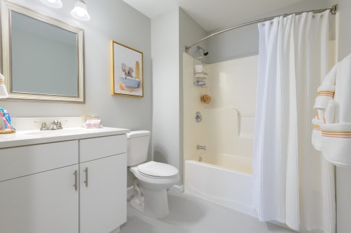 a bathroom with a white toilet next to a white bathtub with a shower curtain
