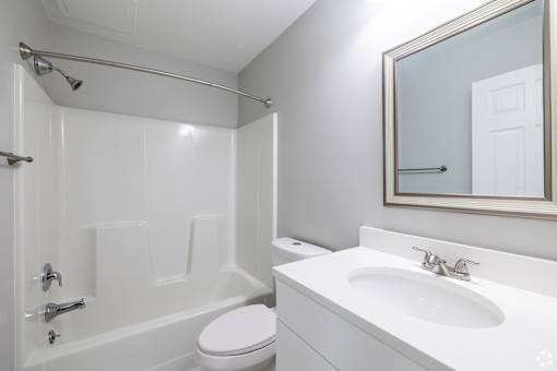 A white bathroom with a toilet, sink, and shower.