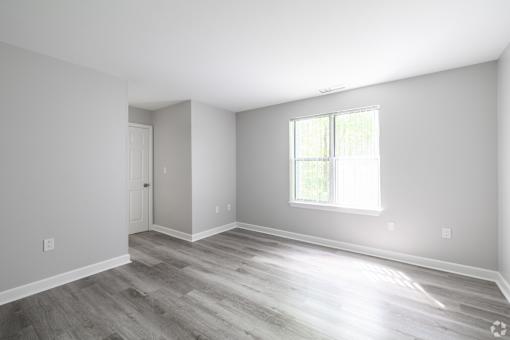 A room with a wooden floor and a window letting in sunlight.