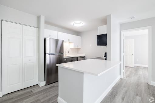 A modern kitchen with white cabinets and a stainless steel refrigerator.