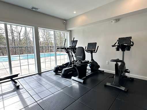 A home gym with a treadmill, stationary bike, and rowing machine.
