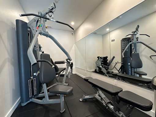 A gym with a mirror, a bench, and a leg press machine.
