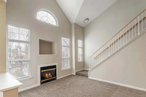 A living room with a fireplace and a staircase.