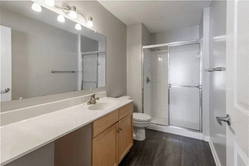 A bathroom with a sink, mirror, toilet, and shower.