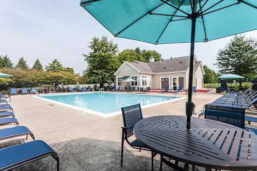 A blue umbrella is on a table next to a pool.