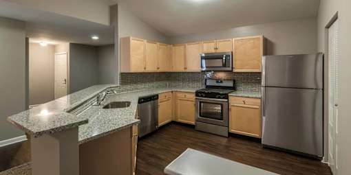 A kitchen with wooden cabinets and a granite countertop.