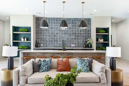 A modern living room with a grey couch and a grey tiled backsplash.