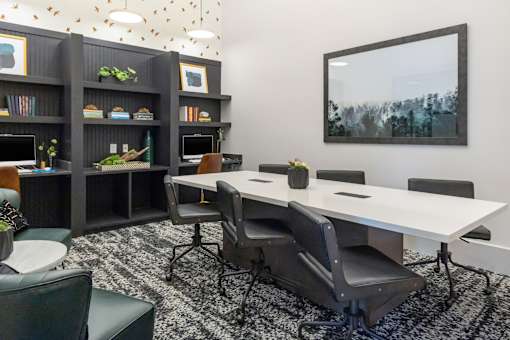 A conference room with a long table, chairs, and a bookshelf.