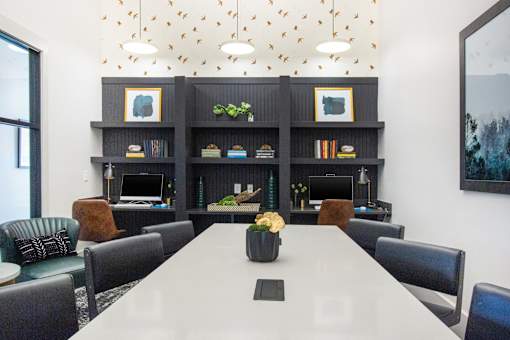 A conference room with a long table, chairs, and a bookshelf with decorative items.