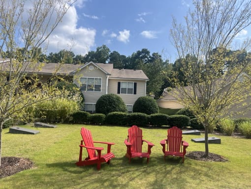 three red chairs sitting in a lawn in front of a house at Addison on Cobblestone, Georgia