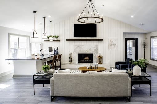 a living room with a fireplace and a kitchen in the backgroundat Addison on Cobblestone, Fayetteville, 30215