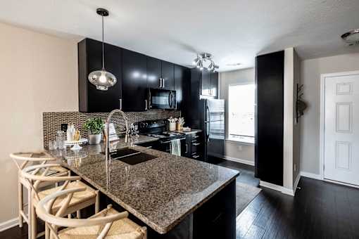 A kitchen with black cabinets and granite countertops at Ansley at Town Center Apartments, Georgia