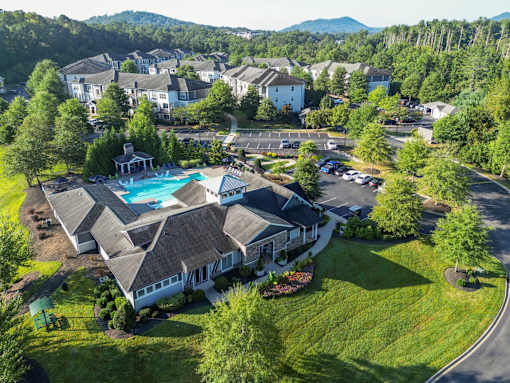 A large house with a pool in the middle of a grassy area.
