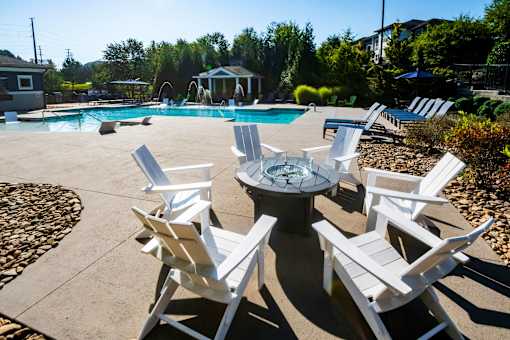 A poolside area with white chairs and a table.