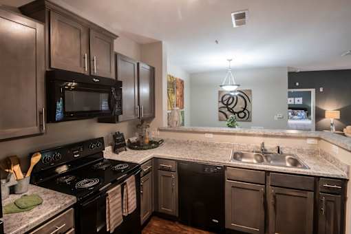 A modern kitchen with dark wood cabinets and black appliances.