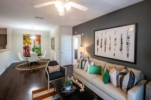 A living room with a white couch, a coffee table, and a painting on the wall.
