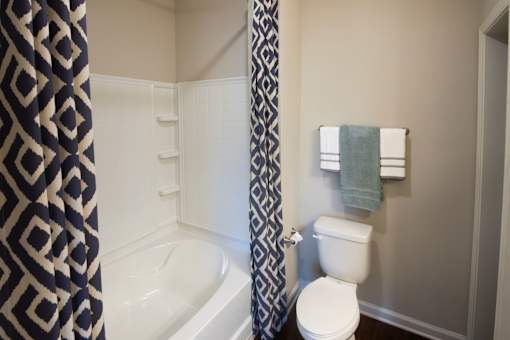 A white toilet sits next to a bathtub in a bathroom.