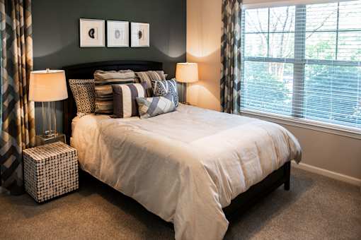 A bedroom with a large bed and two lamps.