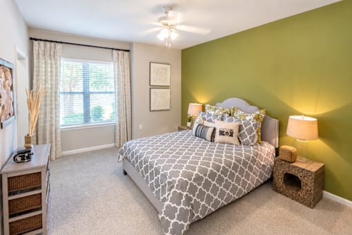 A bedroom with a bed, nightstand, and a window with curtains.