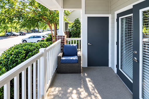 A porch with a white railing and a blue chair.