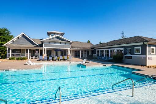 A large swimming pool in front of a building with a white roof.