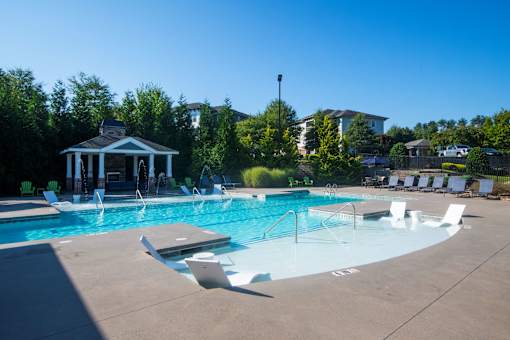 A pool with a gazebo and chairs in the foreground.