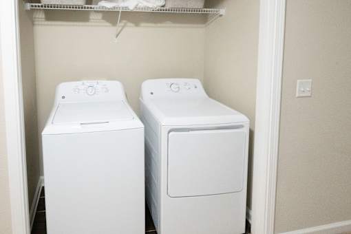 Two white front loading washing machines in a small laundry room.