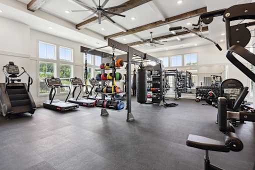 A spacious gym with a variety of equipment including treadmills, weights, and a bench press at Arcadia Cartersville Apartments, Georgia