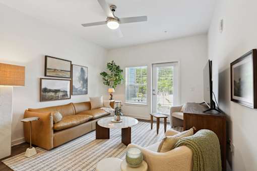A living room with a brown couch, a coffee table, and a ceiling fan. at Arcadia Cartersville Apartments, Cartersville, 30121