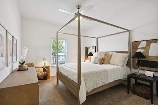 A bedroom with a four poster bed and a table with a lamp on it at Arcadia Cartersville Apartments, Georgia