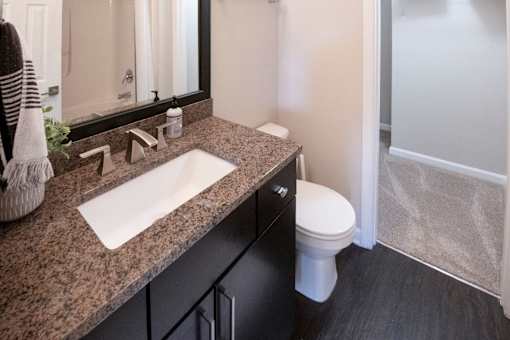 A bathroom with a sink, mirror, toilet and a shower at Ansley at Town Center Apartments, Evans, Georgia