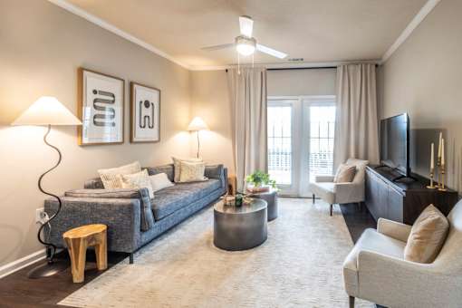 A living room with a grey couch, a round coffee table, and a flat screen TV at Ansley at Town Center Apartments, Georgia, 30809