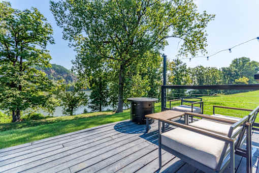 A wooden deck with a bench and a table is surrounded by trees. at Brightwaters Apartments, Little Rock, Arkansas